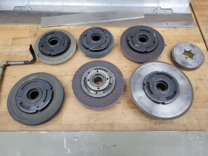 Seven grinding wheels with flanges laid out on a workbench